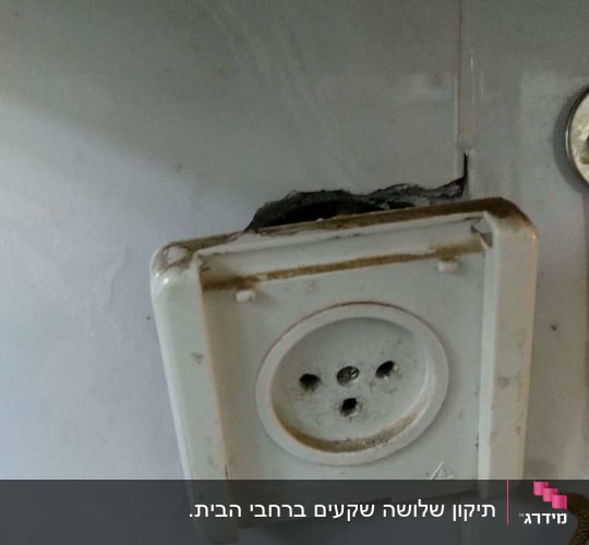 שקע חשמלי ישן עם סדקים בקיר